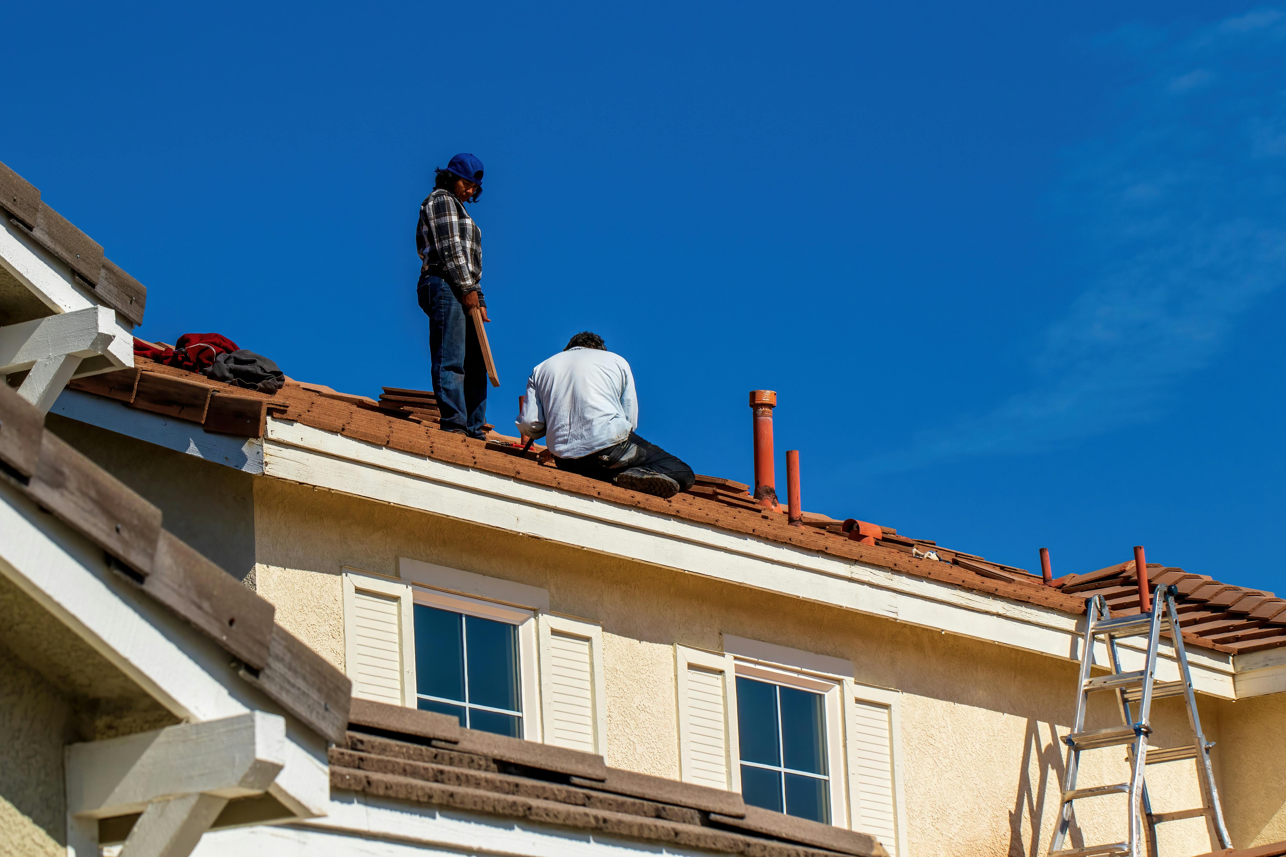 A professional roofer installing architectural asphalt shingles with a pneumatic coil nailer