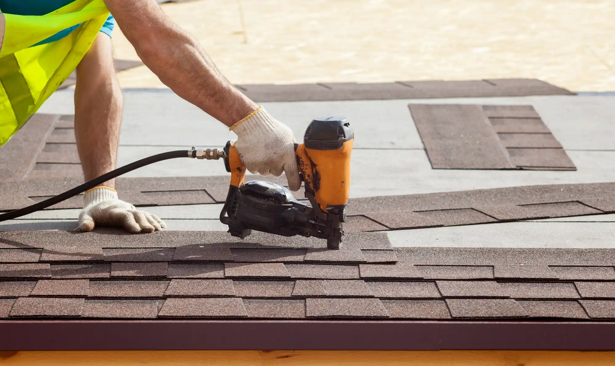 Close-up of a professional installing a row of architectural shingles on a new roof deck